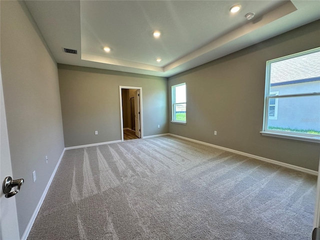 carpeted spare room featuring a raised ceiling, baseboards, recessed lighting, and visible vents