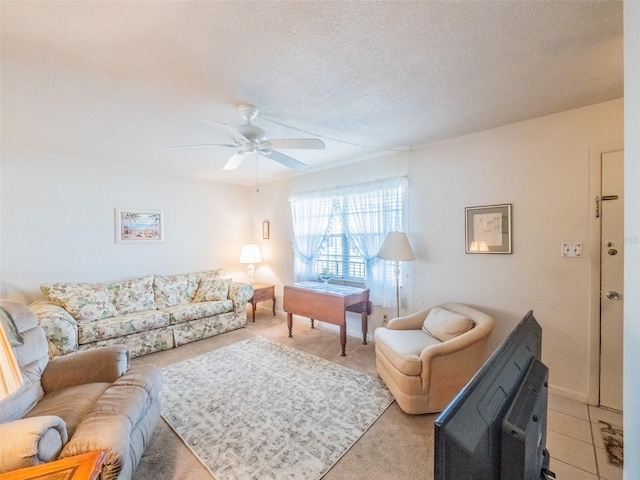 living room featuring light carpet, a ceiling fan, a textured ceiling, and baseboards