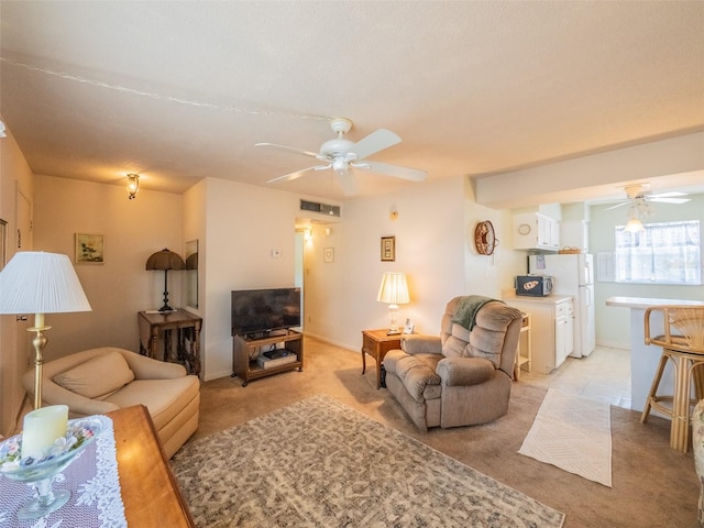 living area featuring visible vents, a ceiling fan, and light colored carpet
