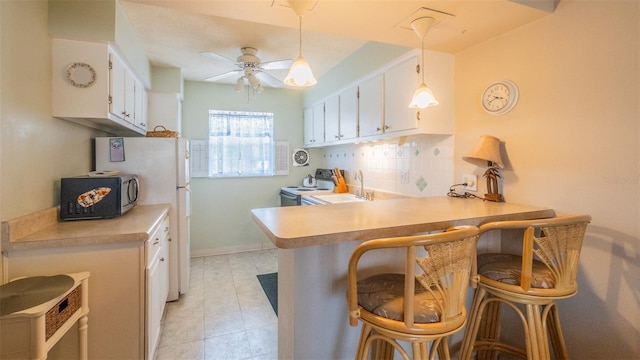 kitchen featuring light countertops, white appliances, a sink, and white cabinetry