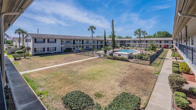 view of community with fence, a yard, and a residential view