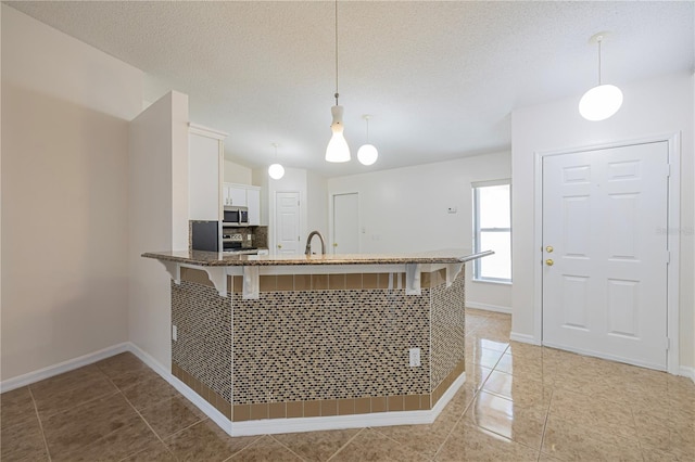 50989 Hwy 27 Unit 371, Davenport, FL 33897 - kitchen featuring appliances with stainless steel finishes, white cabinetry, a peninsula, dark stone counters, and decorative light fixtures