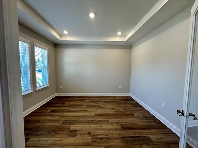 unfurnished room with a raised ceiling, baseboards, dark wood-style flooring, and recessed lighting