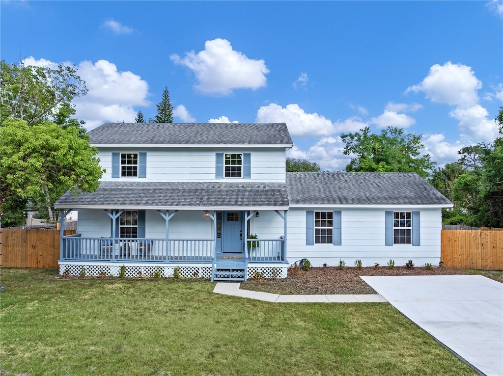 view of front of property featuring roof with shingles, a porch, a front yard, and fence