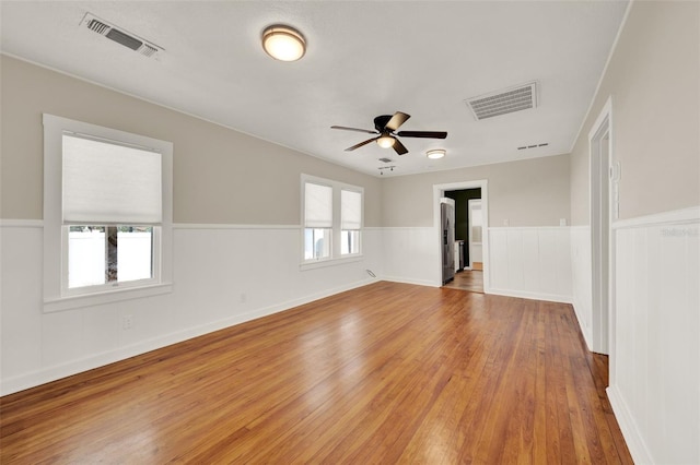 508 10th St, Saint Cloud, FL 34769 - empty room with wood finished floors, ceiling fan, and a wainscoted wall