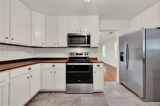 508 10th St, Saint Cloud, FL 34769 - kitchen with stainless steel appliances, butcher block counters, white cabinets, and decorative backsplash