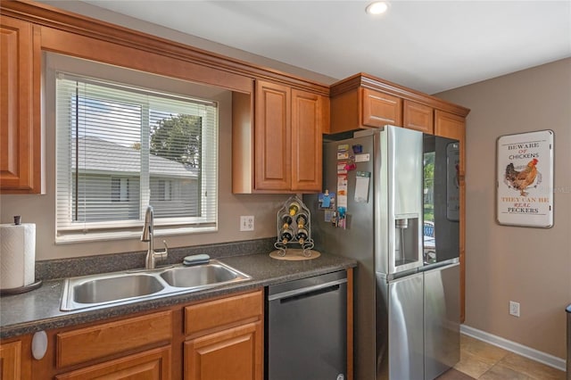 2710 Alabaster Ave, Orlando, FL 32833 - kitchen with dark countertops, a sink, brown cabinetry, baseboards, and appliances with stainless steel finishes