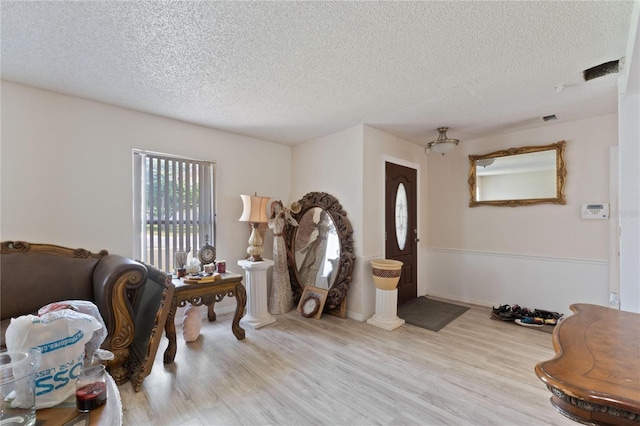 entrance foyer featuring wood finished floors, a textured ceiling, and visible vents