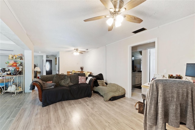 living room with crown molding, visible vents, and a ceiling fan