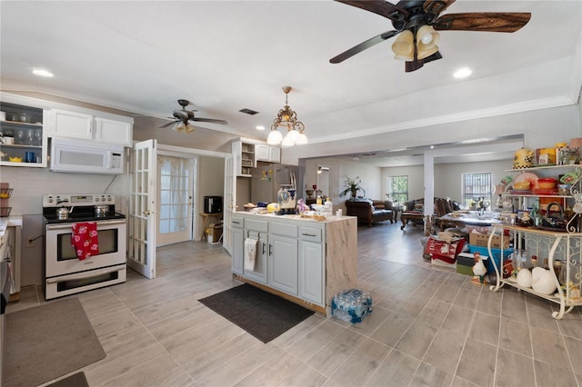 kitchen featuring ornamental molding, open floor plan, ceiling fan, light countertops, and appliances with stainless steel finishes