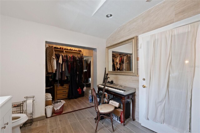 bedroom with vaulted ceiling, wood finished floors, and a closet