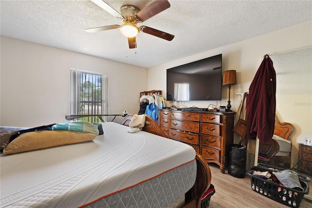 bedroom featuring light wood-style flooring, a textured ceiling, and a ceiling fan