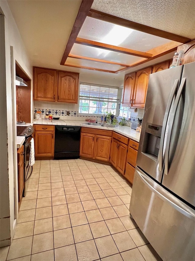 76 Oakdale St, Windermere, FL 34786 - kitchen featuring a sink, brown cabinetry, tasteful backsplash, light tile patterned flooring, and black appliances