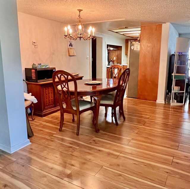 76 Oakdale St, Windermere, FL 34786 - dining area with a notable chandelier, light wood-type flooring, and a textured ceiling