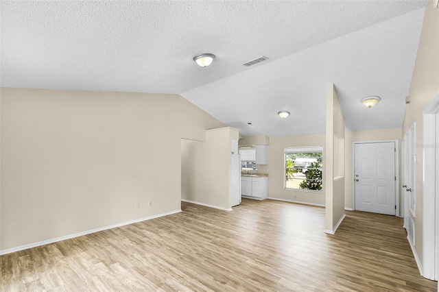 288 Howard Blvd, Longwood, FL 32750 - unfurnished living room featuring baseboards, vaulted ceiling, light wood-type flooring, and a textured ceiling