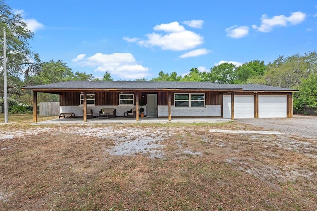 view of front of property with an attached garage, driveway, an outdoor living space, and board and batten siding