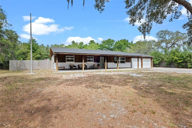 view of front facade with a garage, an outdoor hangout area, driveway, and fence