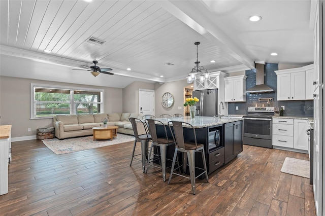 kitchen with stainless steel appliances, open floor plan, visible vents, wall chimney range hood, and an island with sink
