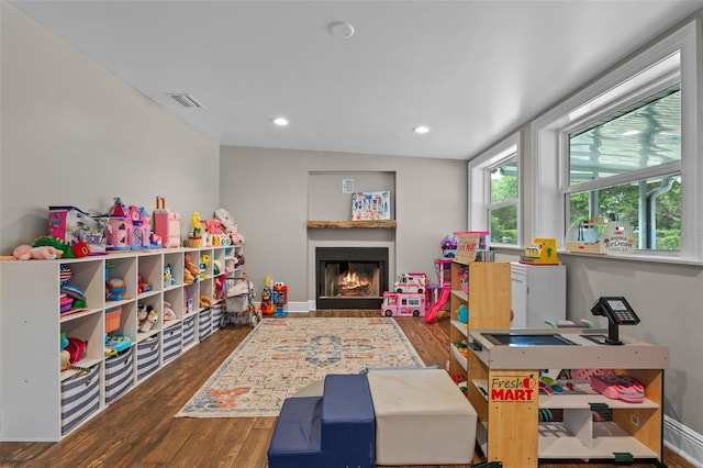 game room with recessed lighting, wood finished floors, visible vents, baseboards, and a lit fireplace