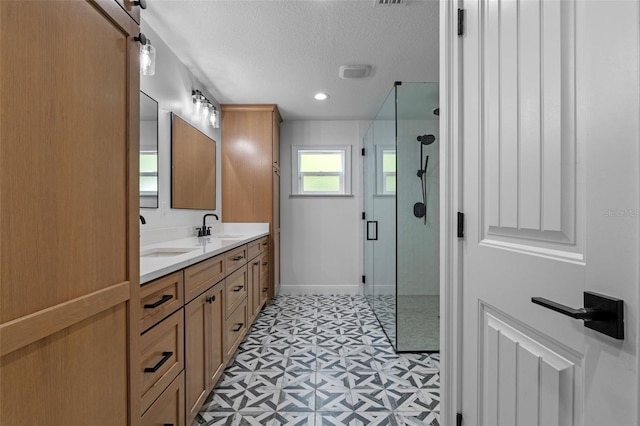 bathroom featuring a shower stall, tile patterned floors, double vanity, a sink, and a textured ceiling