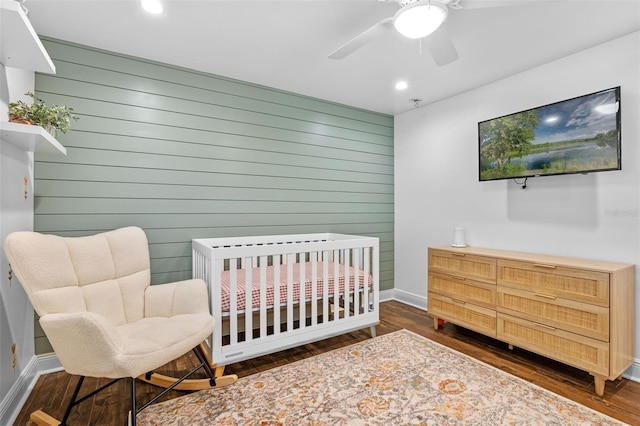 bedroom with a ceiling fan, wood walls, wood finished floors, baseboards, and recessed lighting