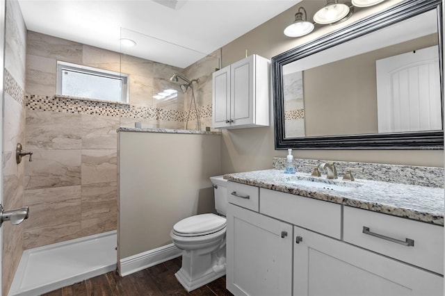 full bathroom featuring wood finished floors, toilet, vanity, a walk in shower, and baseboards