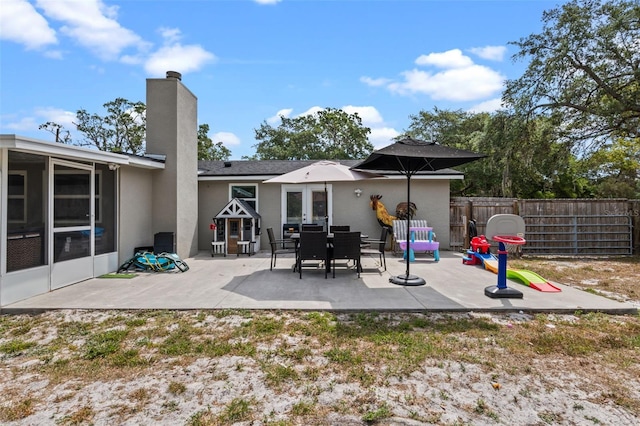 rear view of property featuring fence, a patio area, a chimney, and stucco siding