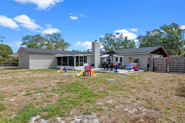 rear view of house with a chimney, fence, stucco siding, a patio, and a sunroom