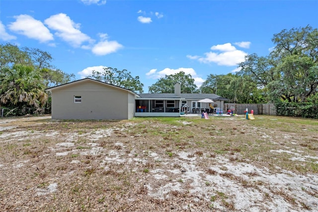 back of property with a chimney, a sunroom, fence, and a patio