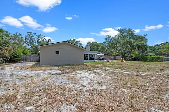 rear view of house featuring a playground and fence