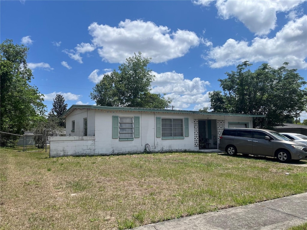 single story home featuring a front lawn and concrete block siding