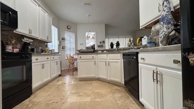7415 Devereaux St, Reunion, FL 34747 - kitchen with black appliances, a peninsula, white cabinets, and hanging light fixtures