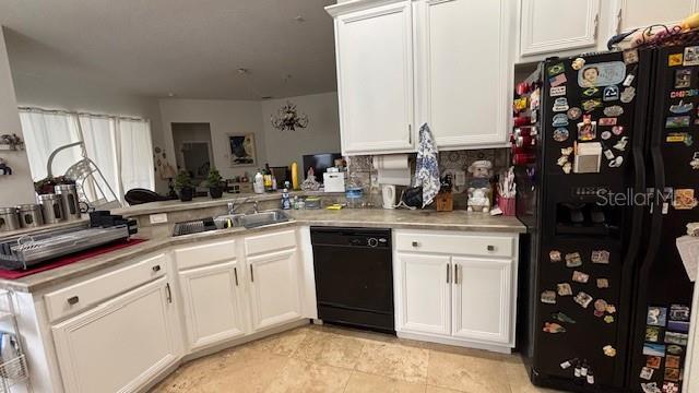 7415 Devereaux St, Reunion, FL 34747 - kitchen with black appliances, light countertops, and white cabinets