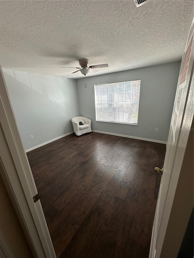 unfurnished room featuring a textured ceiling, a ceiling fan, dark wood-style floors, and baseboards