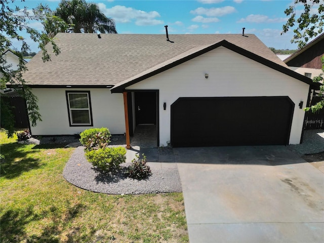 ranch-style home with an attached garage, a shingled roof, driveway, and a front yard