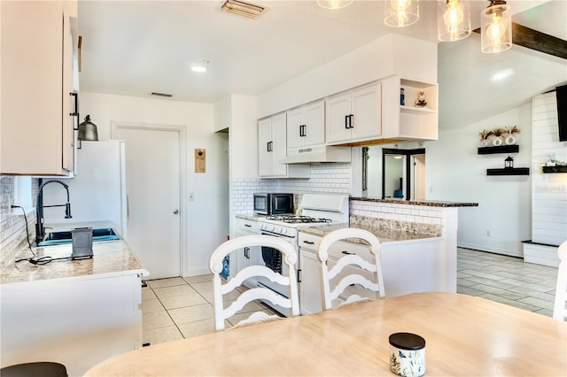 3328 Fox Rdg, Winter Haven, FL 33884 - kitchen featuring gas range gas stove, under cabinet range hood, decorative backsplash, white cabinets, and open shelves
