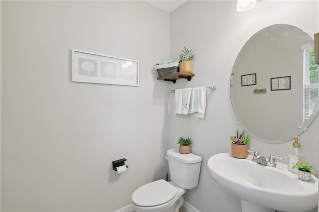 half bath with a sink, toilet, and baseboards