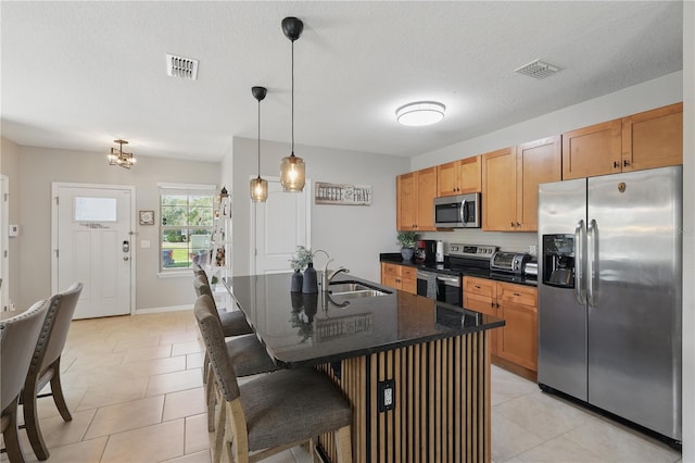 kitchen featuring appliances with stainless steel finishes, a sink, a kitchen breakfast bar, and light tile patterned floors