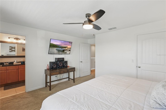 bedroom with light carpet, baseboards, ensuite bath, and a ceiling fan