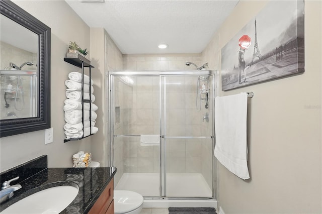 bathroom with a stall shower, toilet, vanity, and a textured ceiling