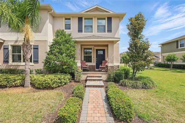 view of front of home with stucco siding, a front yard, and a porch