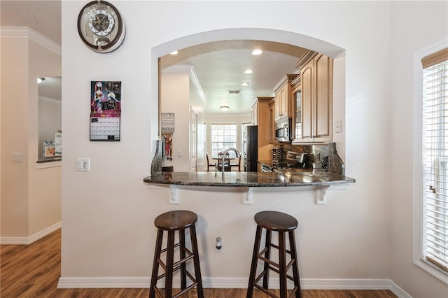 14208 Morning Frost Dr, Orlando, FL 32828 - kitchen featuring arched walkways, stainless steel appliances, a breakfast bar area, and crown molding