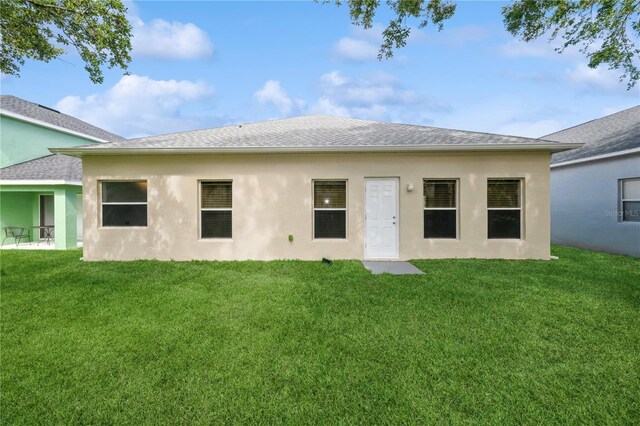 14208 Morning Frost Dr, Orlando, FL 32828 - rear view of house with a shingled roof, stucco siding, and a lawn
