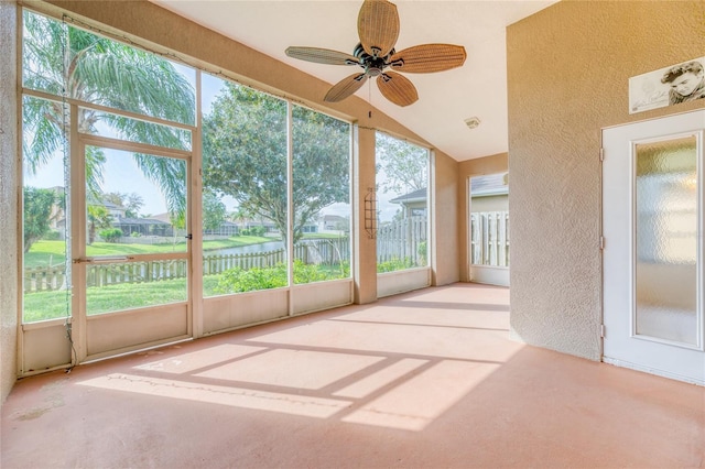 unfurnished sunroom with a ceiling fan, a textured wall, a healthy amount of sunlight, and a water view