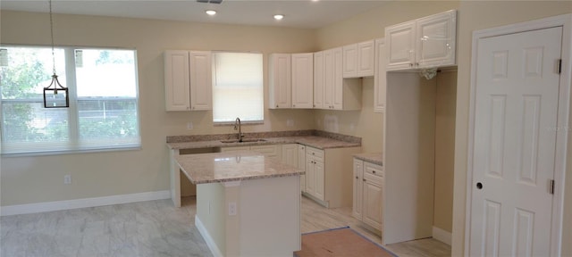 5815 Twisted Oaks Dr, Sebring, FL 33876 - kitchen featuring a sink, a center island, light stone counters, white cabinets, and baseboards