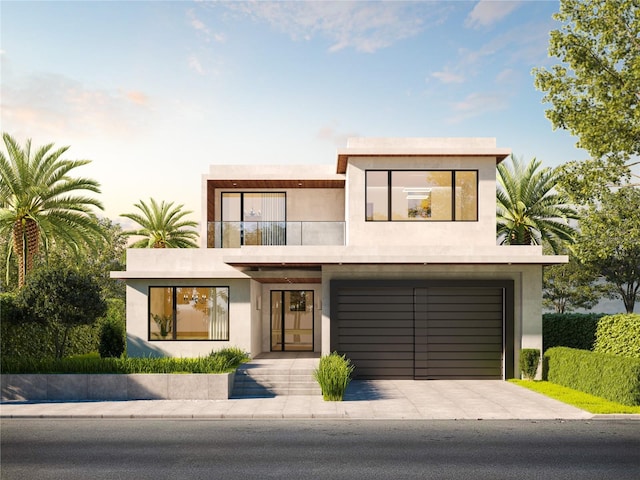 contemporary home featuring a garage, stucco siding, concrete driveway, and a balcony