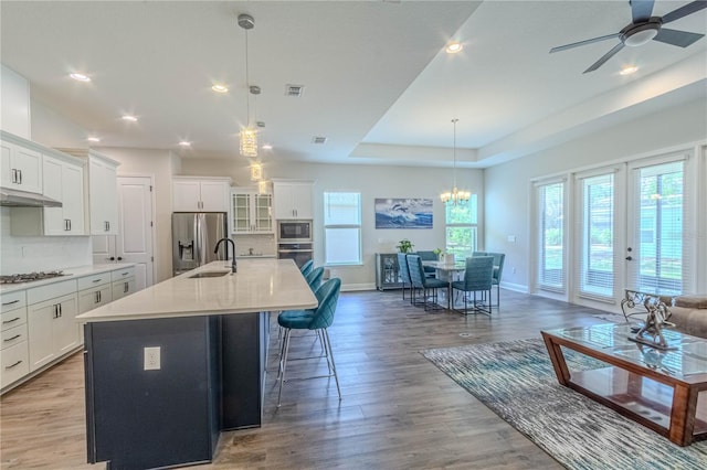 kitchen with a kitchen island with sink, a breakfast bar, baseboards, appliances with stainless steel finishes, and visible vents