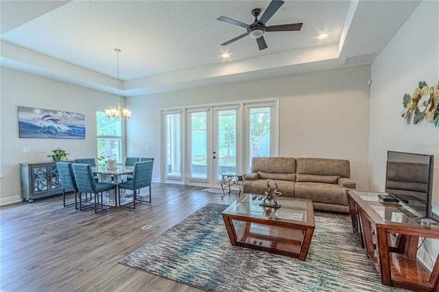 living area featuring a wealth of natural light, wood finished floors, and a tray ceiling