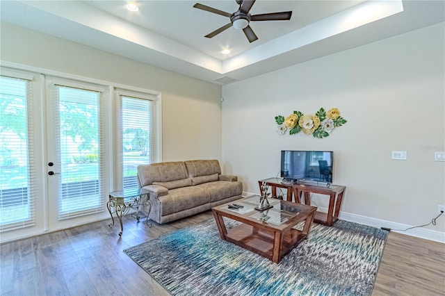 living room featuring recessed lighting, a tray ceiling, wood finished floors, a ceiling fan, and baseboards