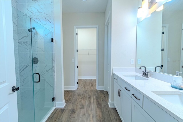 full bathroom with wood finished floors, a spacious closet, a stall shower, and a sink